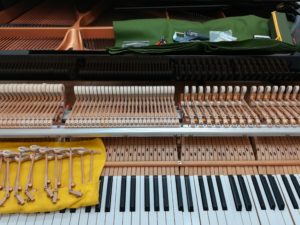 湿気が原因の動作不良のグランドピアノ部品を修理する様子